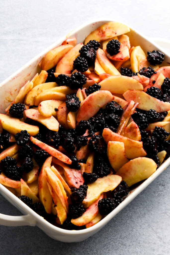 apples peeled and sliced mixed with blackberries in a pan