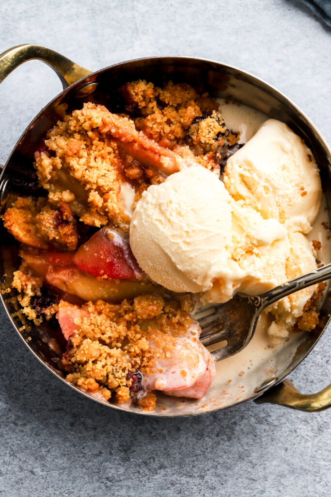 apple blackberry crumble in a bowl served with ice cream
