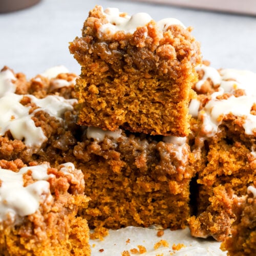 slices of pumpkin coffee cake with streusel topping and cream cheese glaze stacked on top of each other