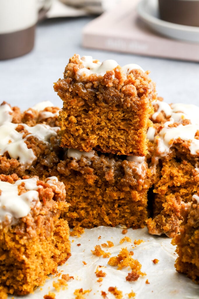 slices of pumpkin coffee cake with streusel topping and cream cheese glaze stacked on top of each other