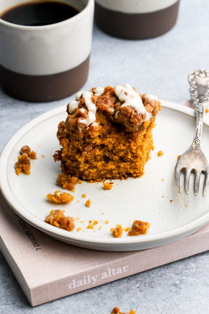 one piece of pumpkin coffee cake with a bite missing next to a fork in a plate