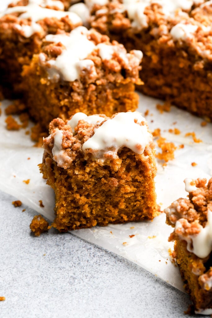 pumpkin coffee cake with streusel and cream cheese drizzle with one piece moved