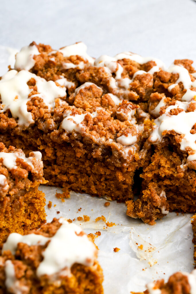 pumpkin coffee cake with streusel and cream cheese frosting sliced so you can see the side texture