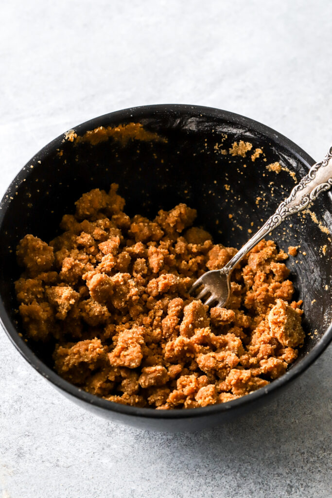 brown sugar streusel being mixed in a bowl with a fork