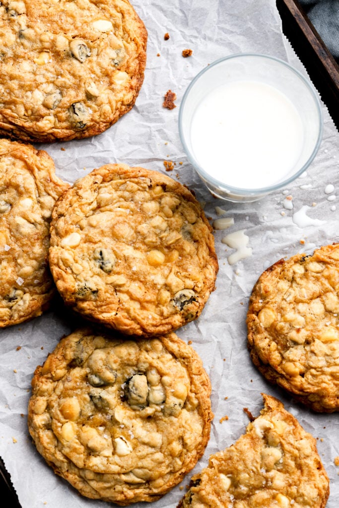 white chocolate oatmeal raisin cookies on a cookie sheet with a glass of milk
