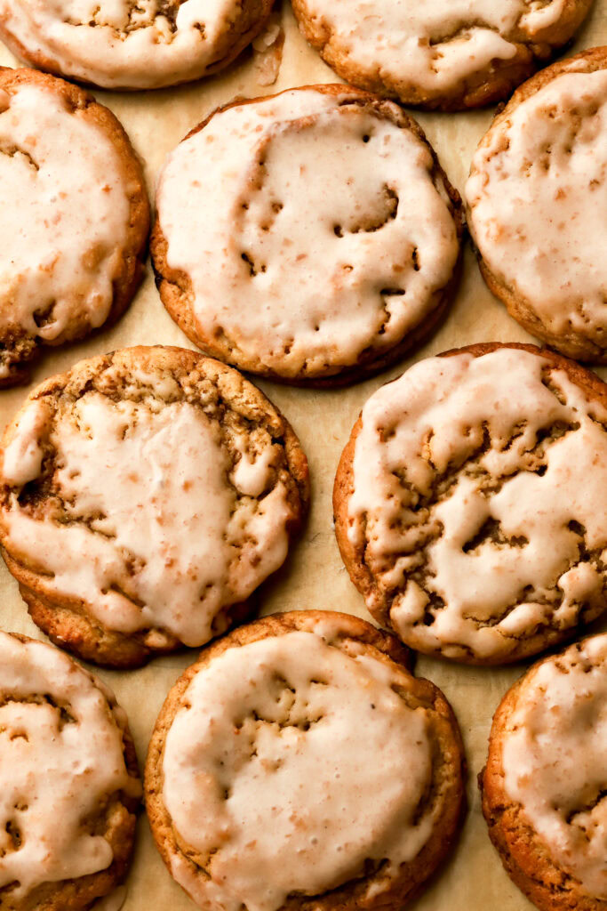 apple butter cookies on a pan with brown parchment paper, dipped in icing