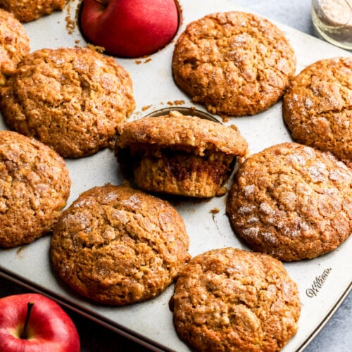 Apple muffins in a baking pan with red apples