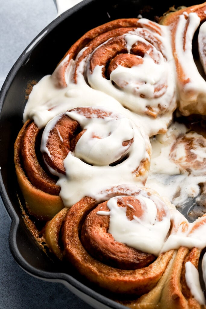 close up of cinnamon rolls in a pan with cream cheese frosting