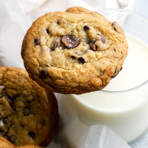 chocolate chip cookie sitting on a cup of milk