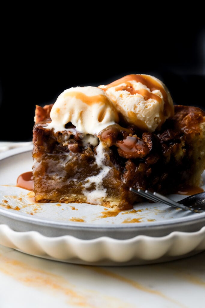 slice of pecan pie topped with vanilla ice cream and caramel sauce