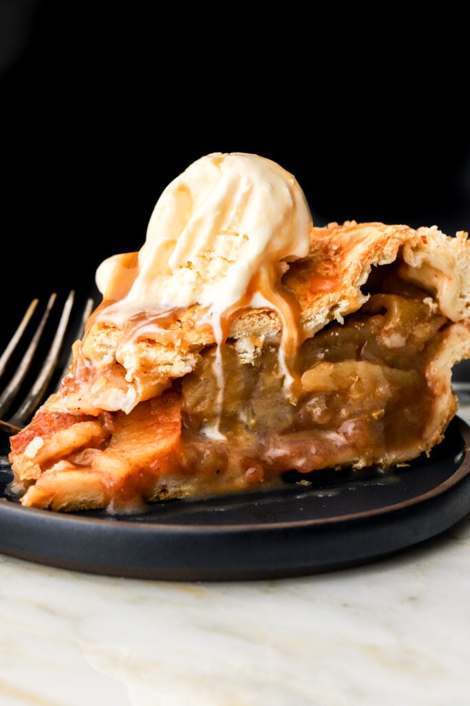 slice of apple pie with vanilla ice cream on a plate