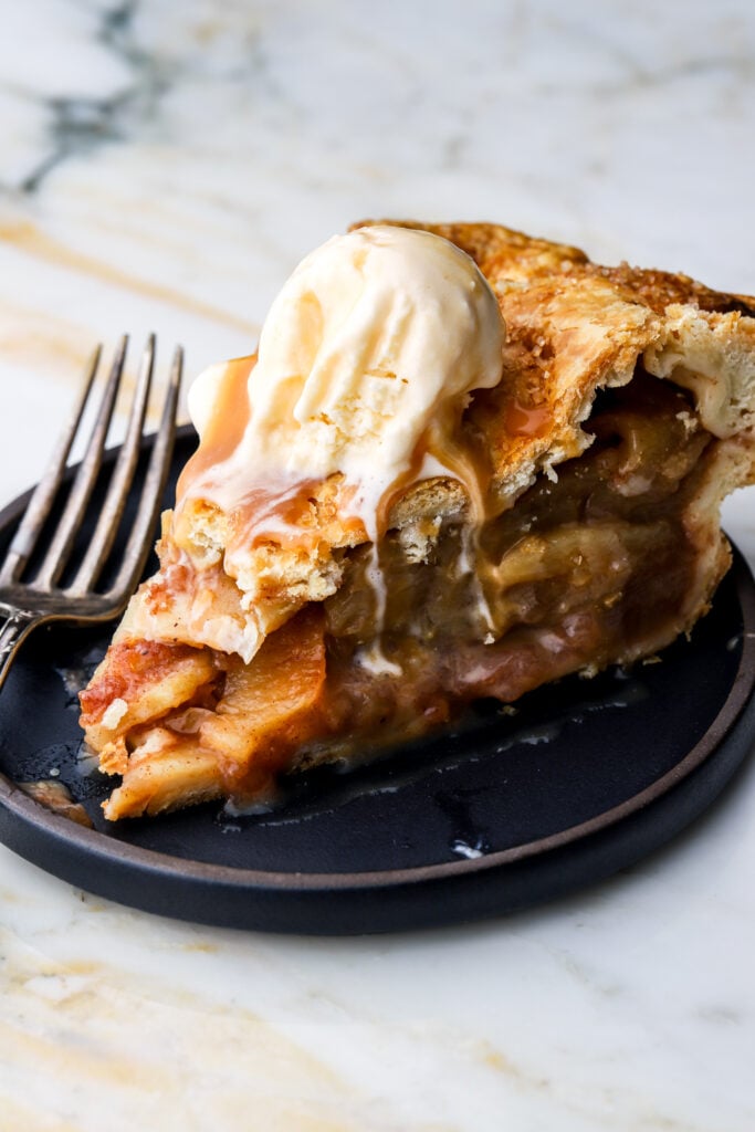 slice of apple pie with vanilla ice cream on a plate