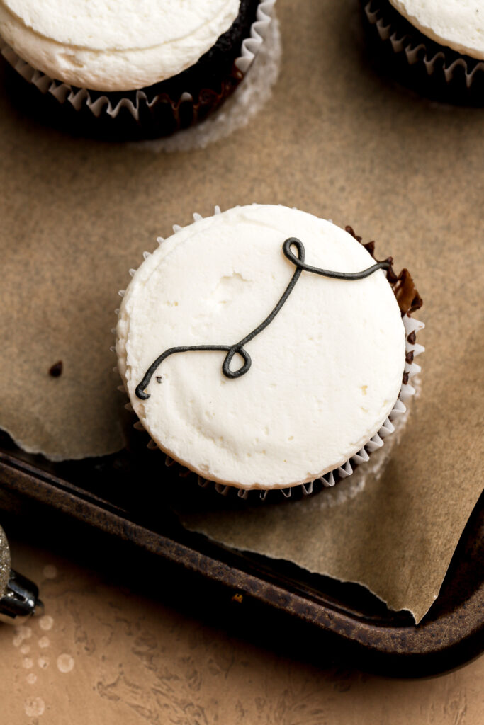 squiggle of black frosting piped on a cupcake for the string lights
