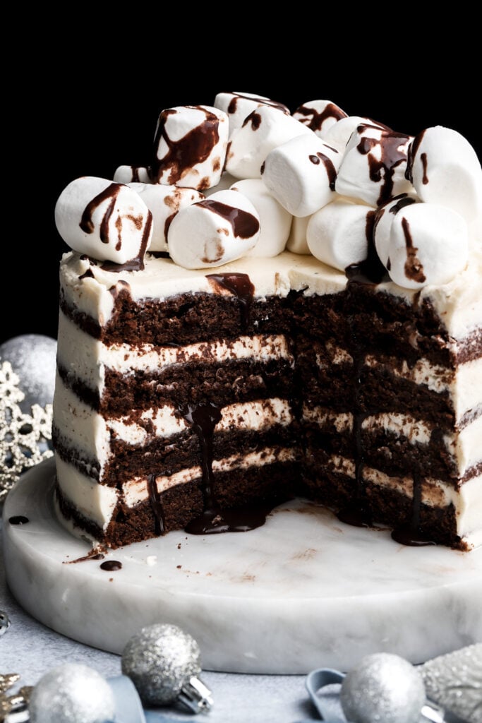 hot chocolate cake topped with marshmallows and chocolate fudge sauce with a few slices removed