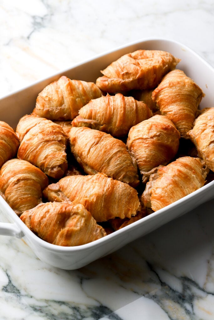 layer croissants in the casserole dish on top of the butter