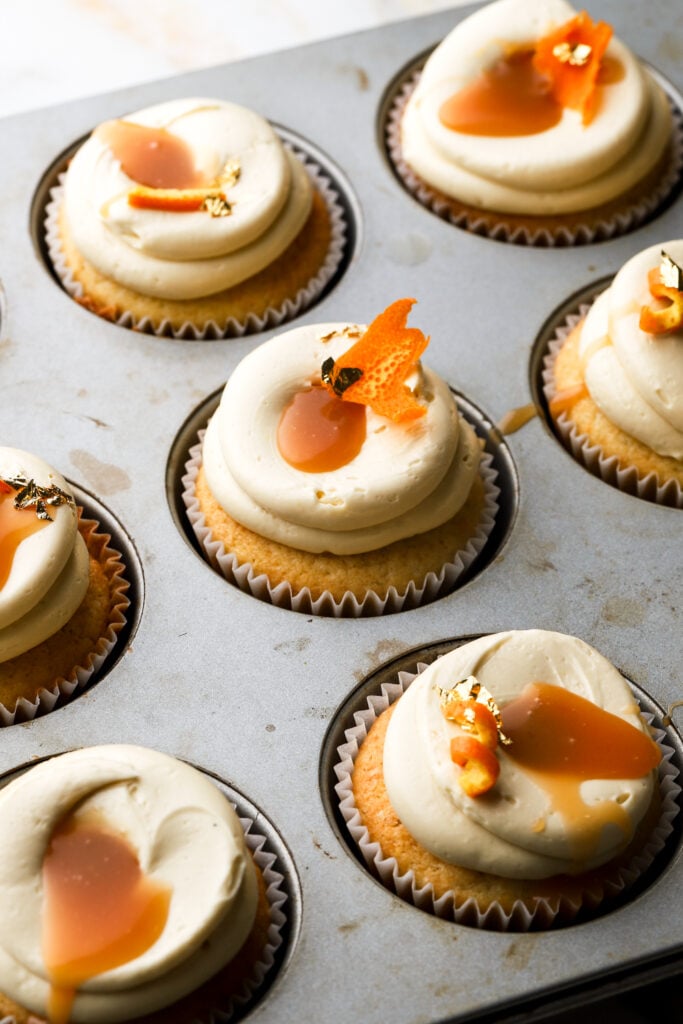 orange cupcakes decorated with orange peel and a gold leaf