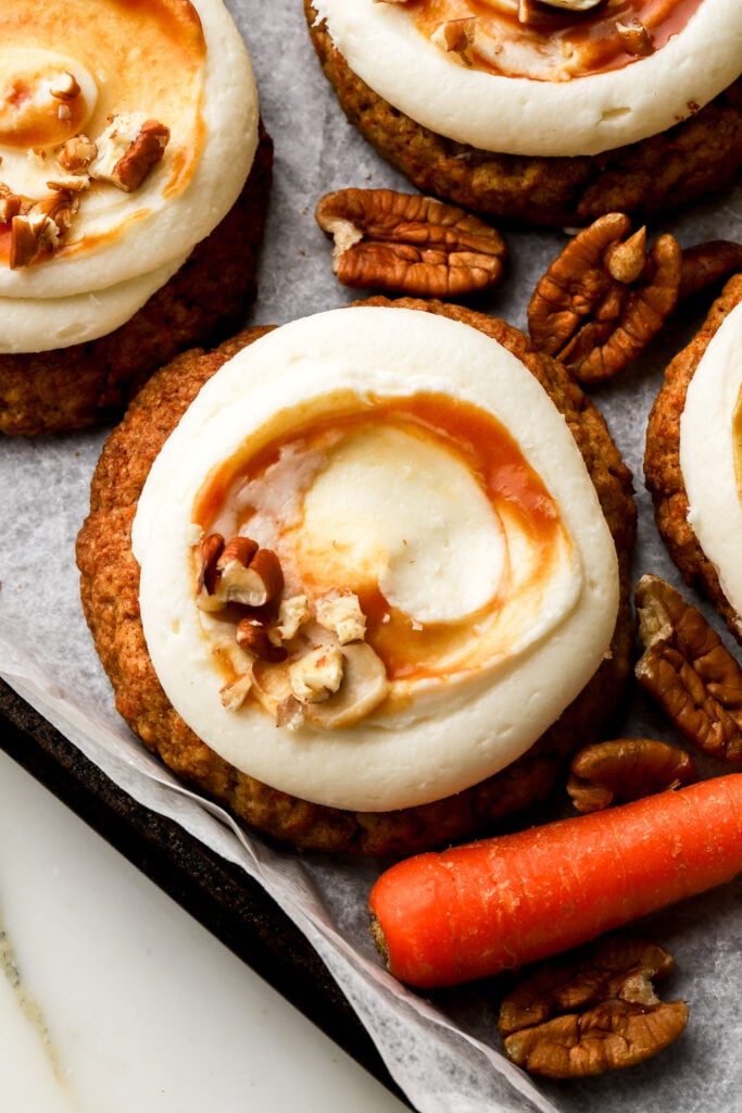 close up of carrot cake cookies frosted with cream cheese frosting and caramel sauce