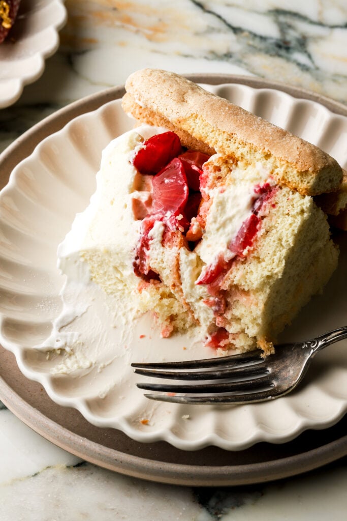 slice of strawberry charlotte cake on a plate with a fork