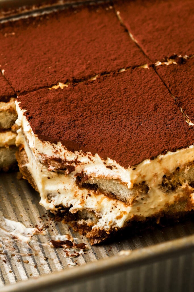 tiramisu in a tray sliced with a bite taken out