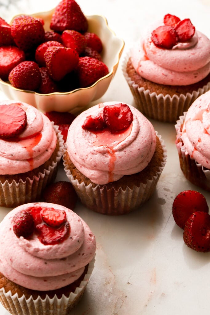 strawberry cupcakes with a bowl of strawberries