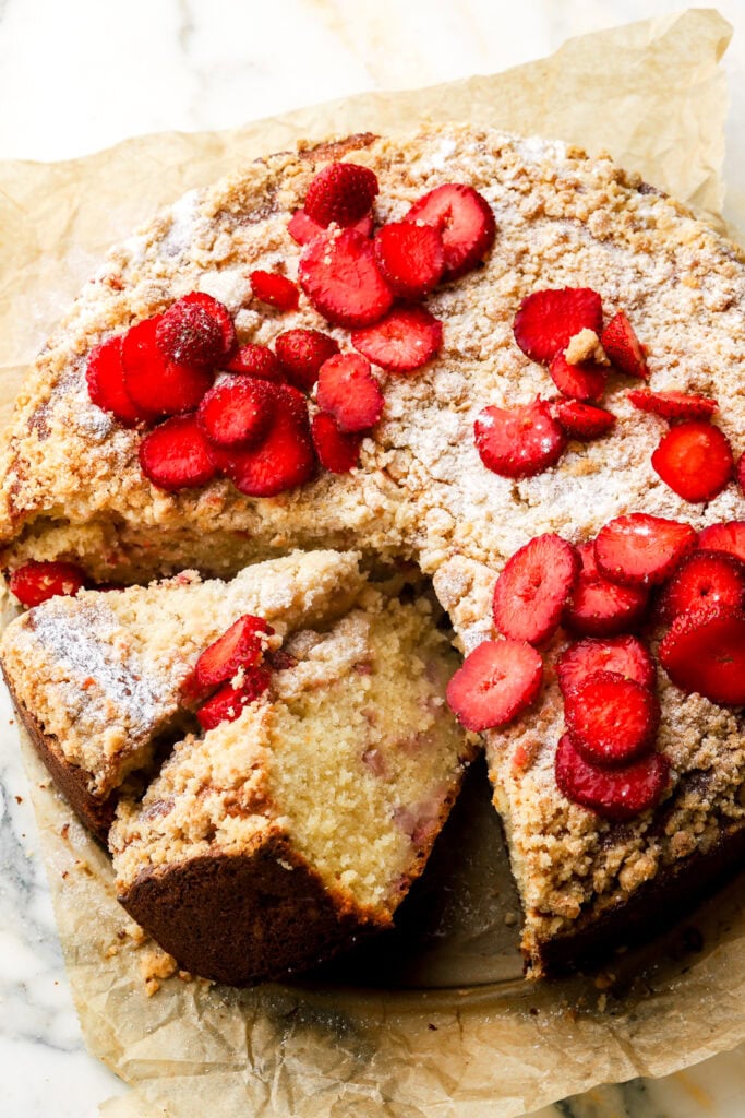 strawberry muffin cake sliced and topped with powdered sugar and strawberry slices