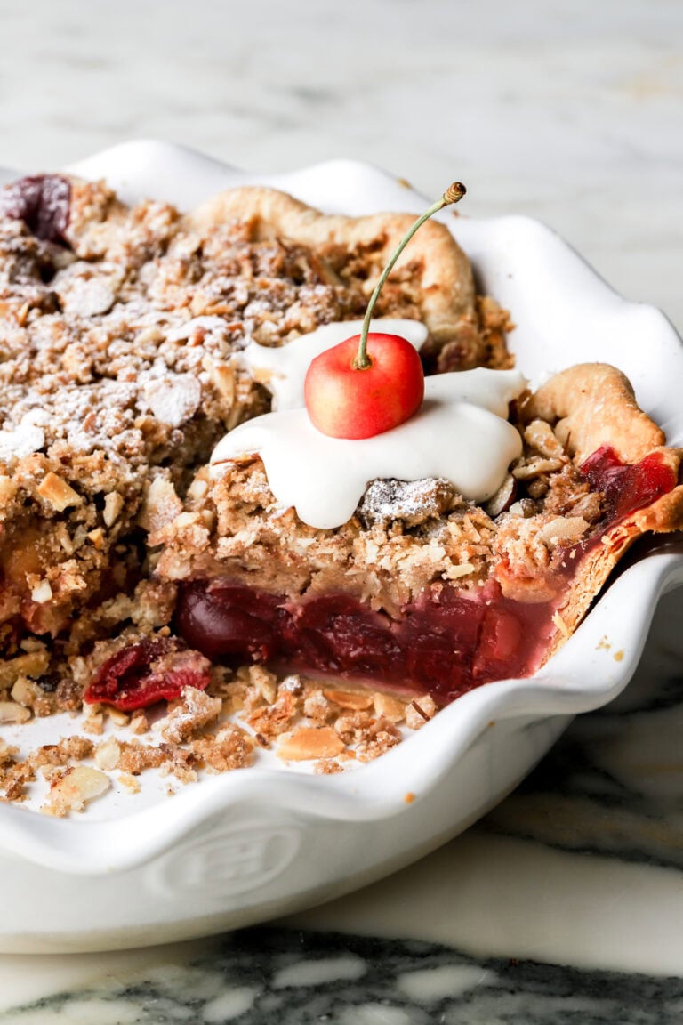 cherry pie with streusel topping and cream and cherry on top