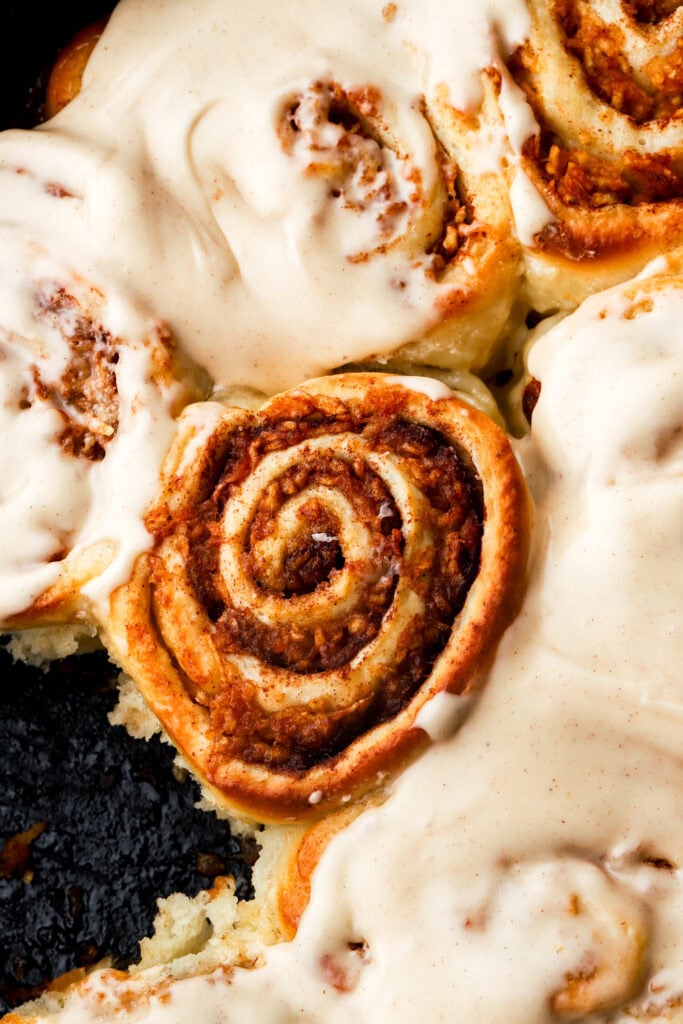 apple cinnamon rolls close up with surrounding ones frosted