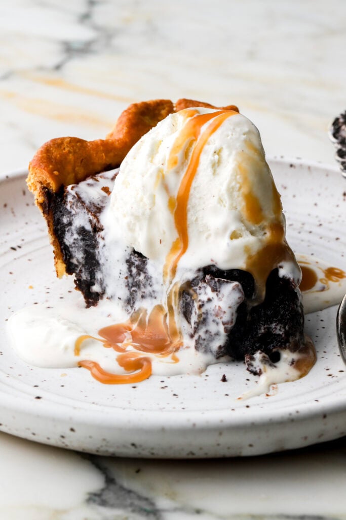 slice of brownie pie topped with vanilla ice cream and caramel sauce