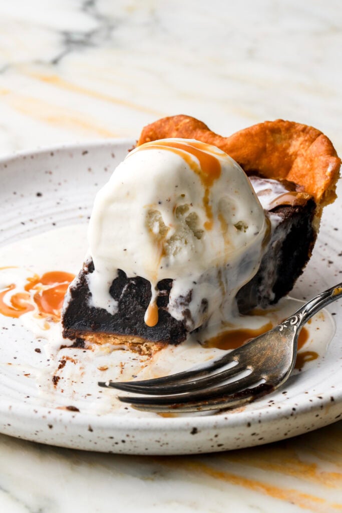 slice of brownie pie topped with vanilla ice cream and caramel sauce