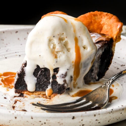 slice of brownie pie topped with vanilla ice cream and caramel sauce