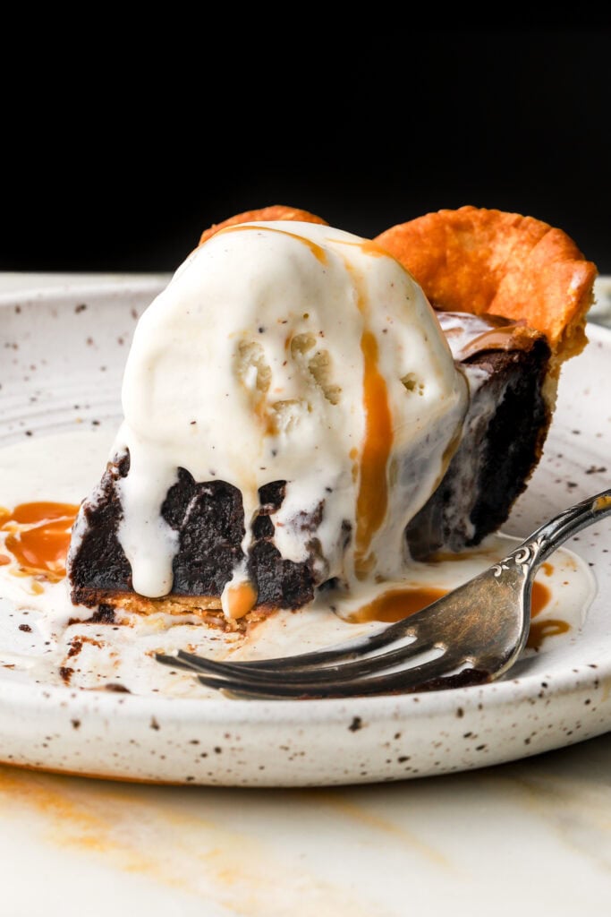 slice of brownie pie topped with vanilla ice cream and caramel sauce