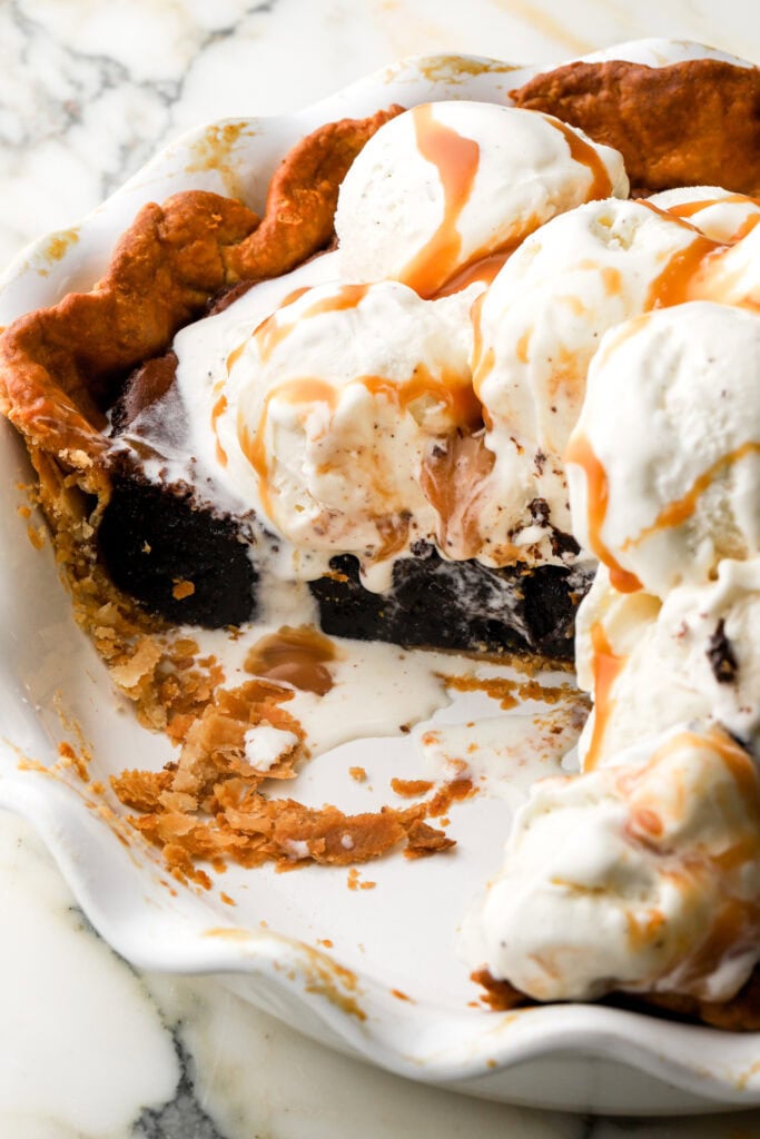 brownie pie in pie dish topped with vanilla ice cream