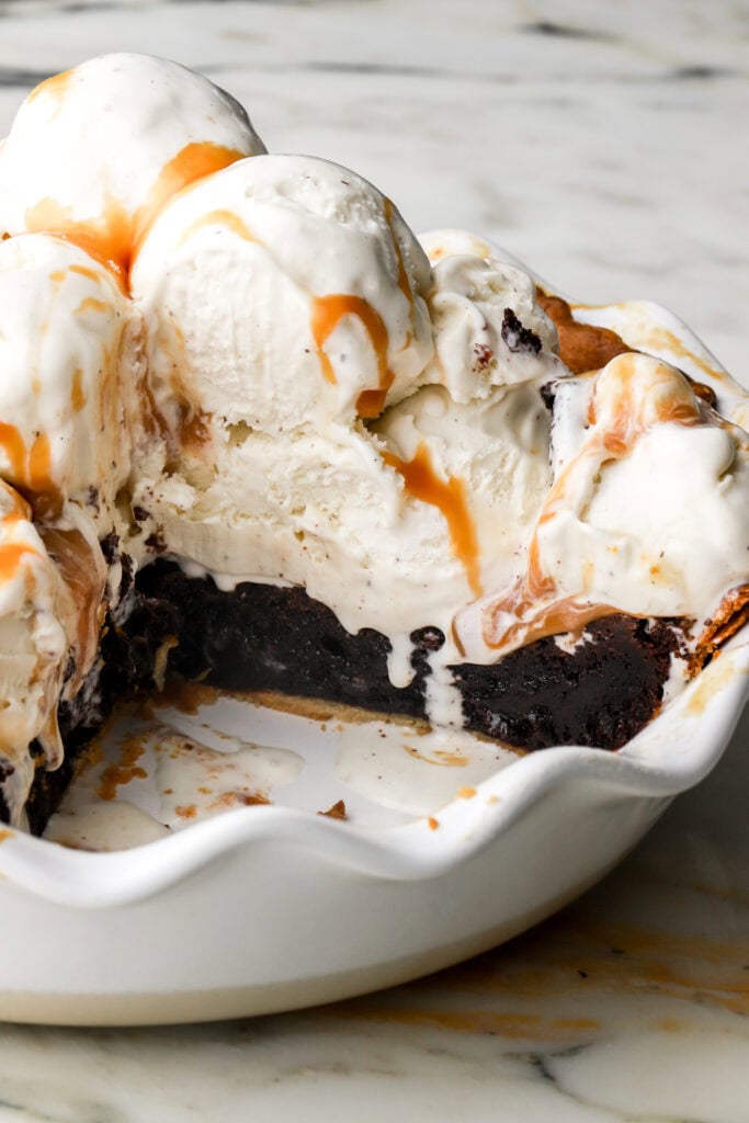 brownie pie in pie dish topped with vanilla ice cream 