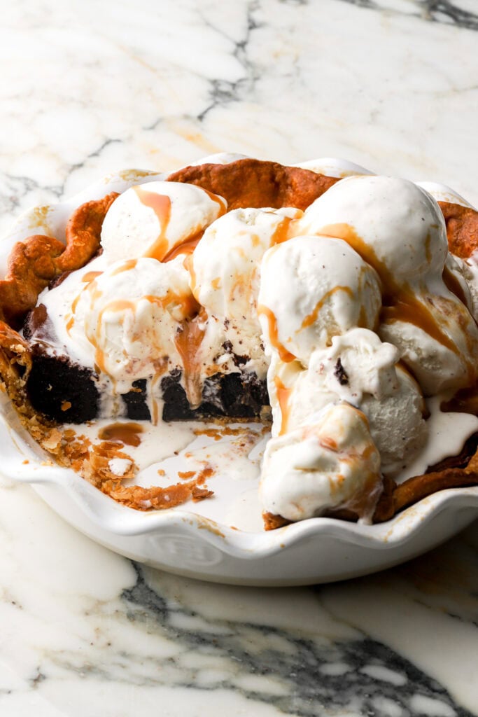 brownie pie in pie dish topped with vanilla ice cream