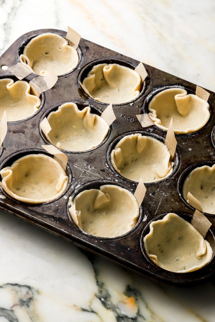 raw pie dough placed into muffin tins