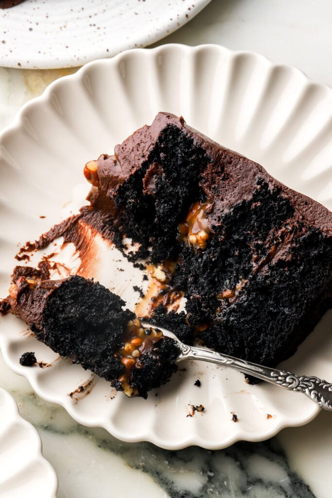 slice of chocolate turtle cake with a piece on a fork