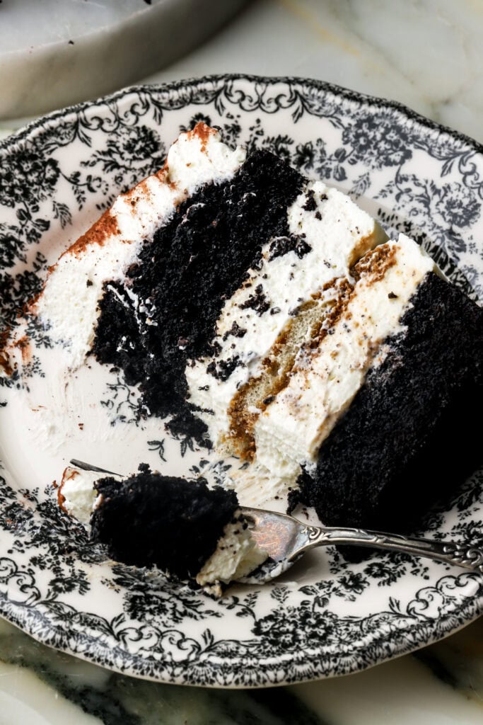 slice of chocolate tiramisu cake on a plate with a bite taken out