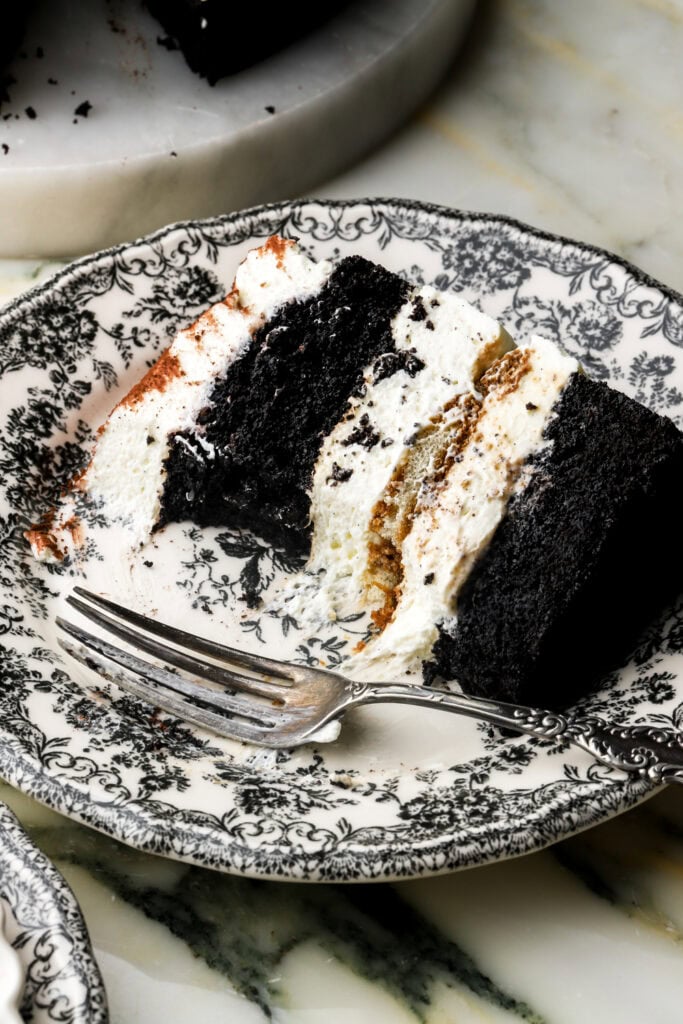 slice of chocolate tiramisu cake on a plate with a bite taken out