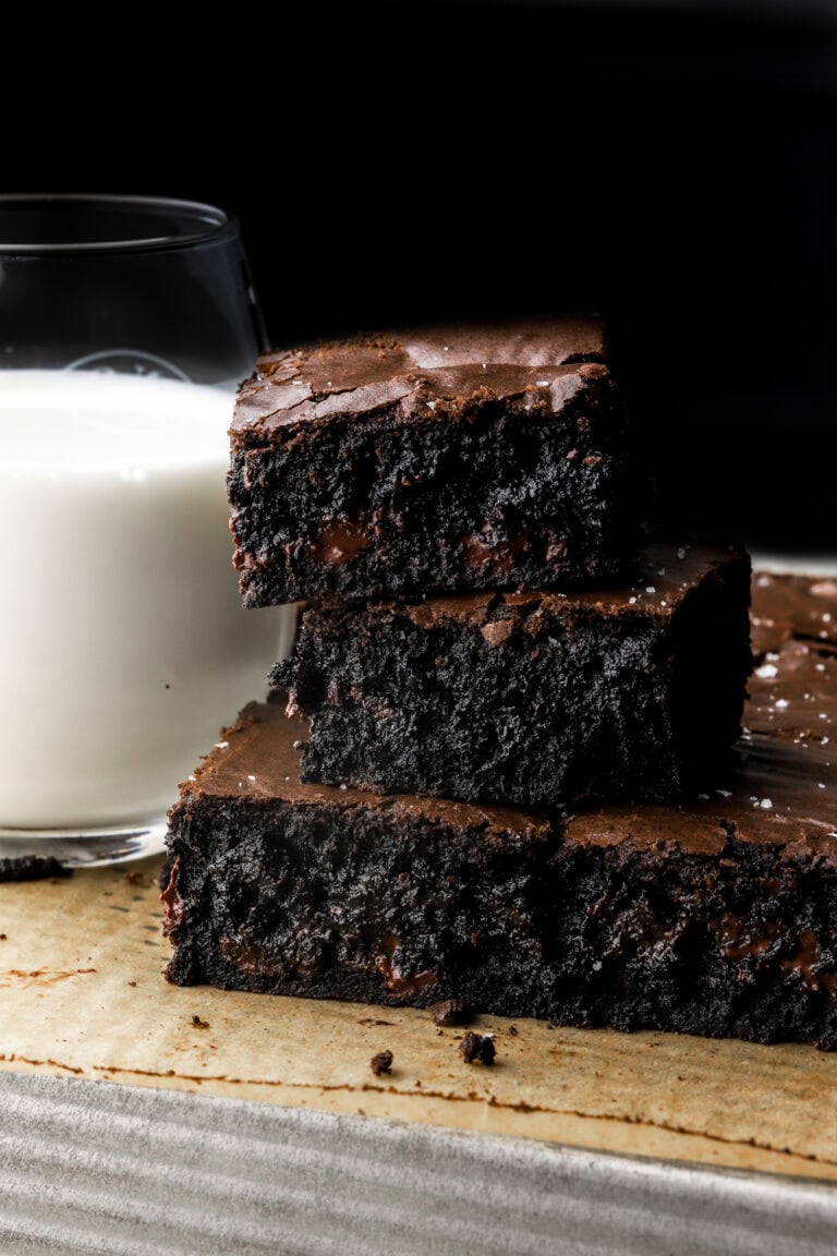 black cocoa brownies with a cup of milk next to them.