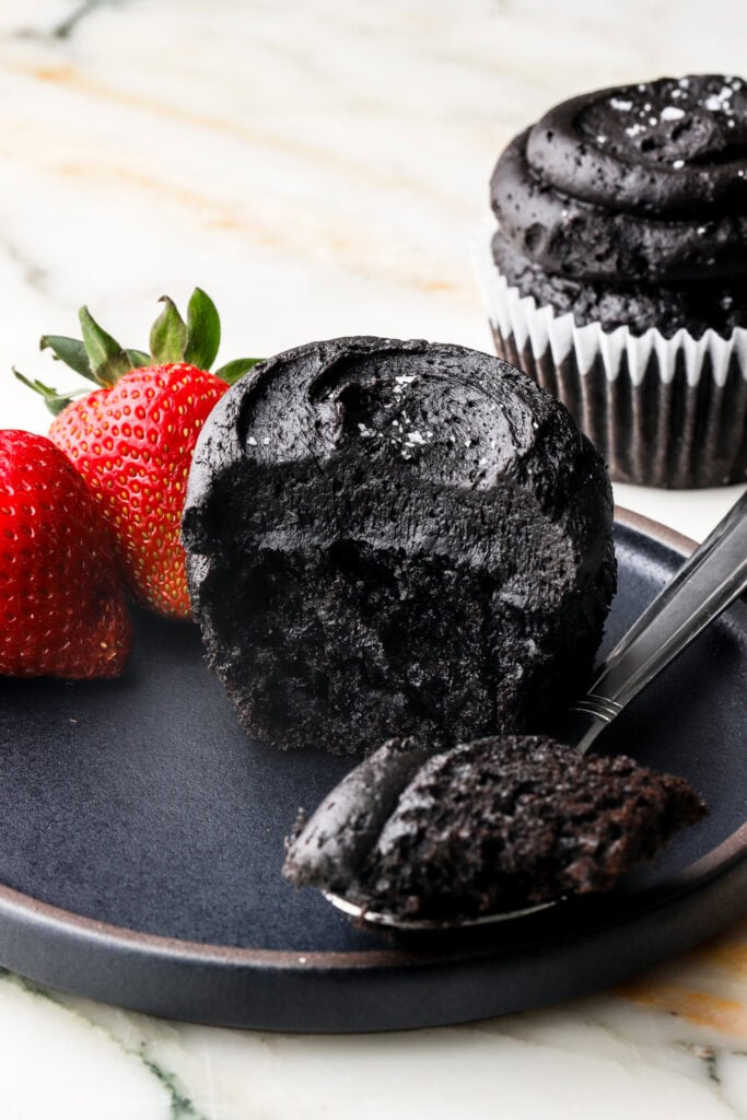 black cocoa cupcakes on a plate with a bite taken out