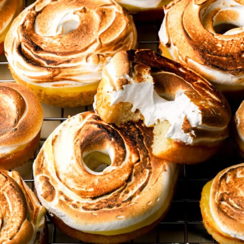 lemon meringue donuts on a tray and a bite taken out