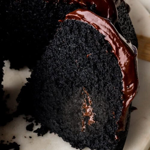 slice of black cocoa bundt cake with chocolate ganache on top