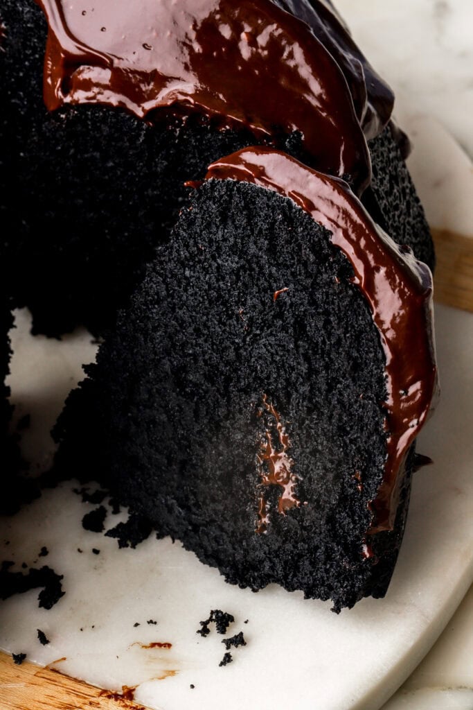 slice of black cocoa bundt cake with chocolate ganache on top