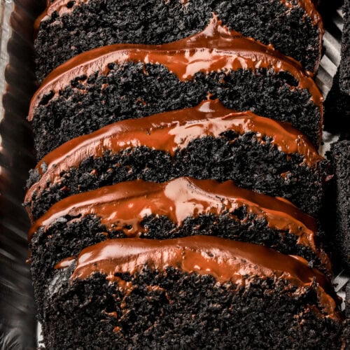 black cocoa loaf cake with chocolate ganache sliced in a pan