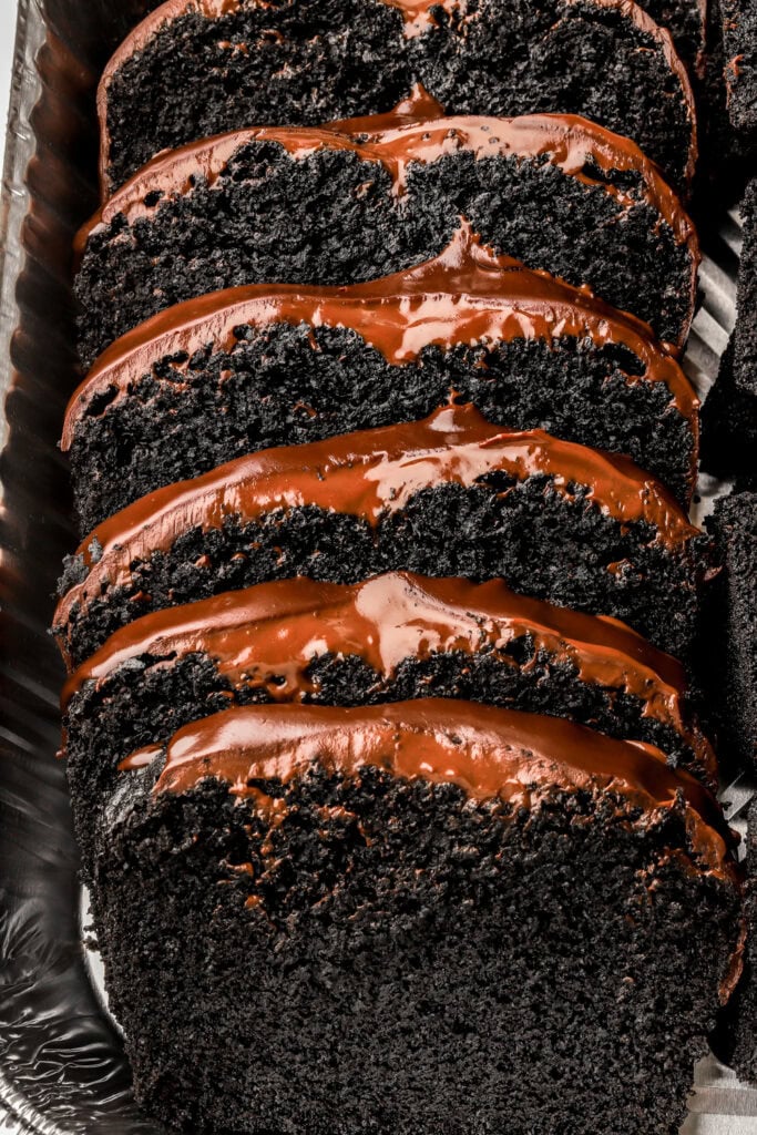 black cocoa loaf cake with chocolate ganache sliced in a pan