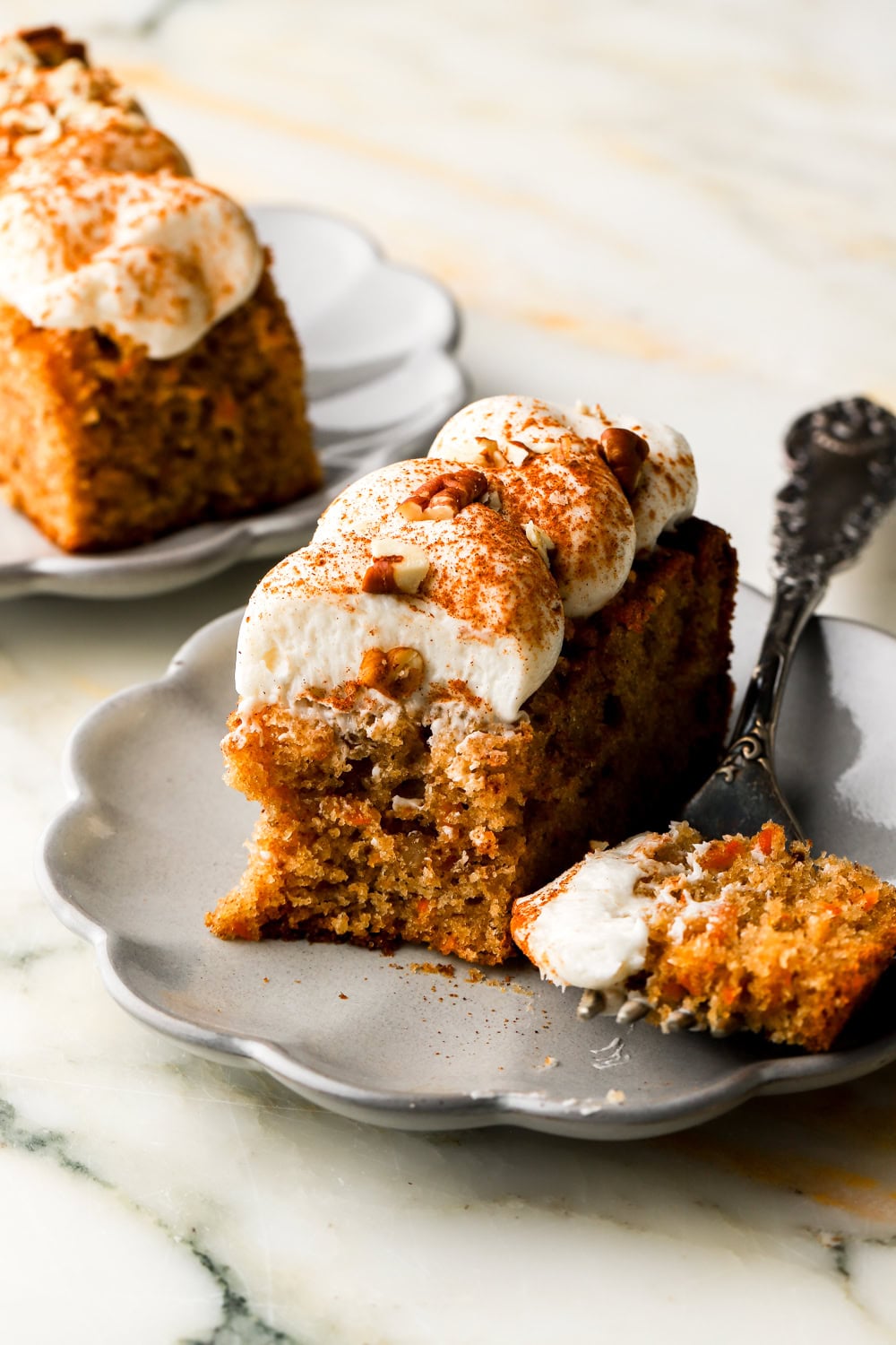 carrot cake sheet cake frosted with cream cheese frosting on a plate with a bite taken out