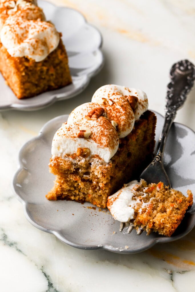 slice of carrot cake on a plate with piped cream cheese frosting