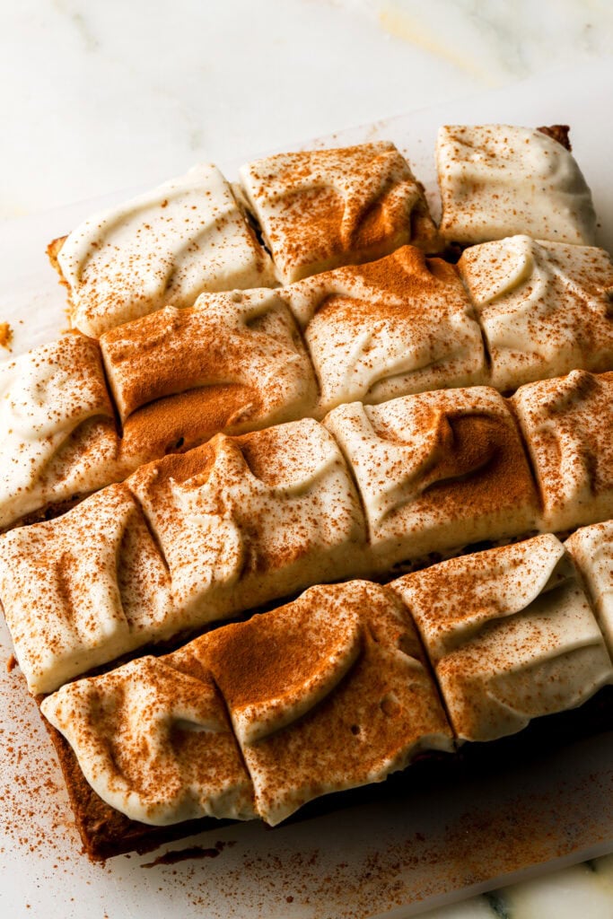 carrot cake cookie bars frosted with cream cheese frosting and dusted with cinnamon