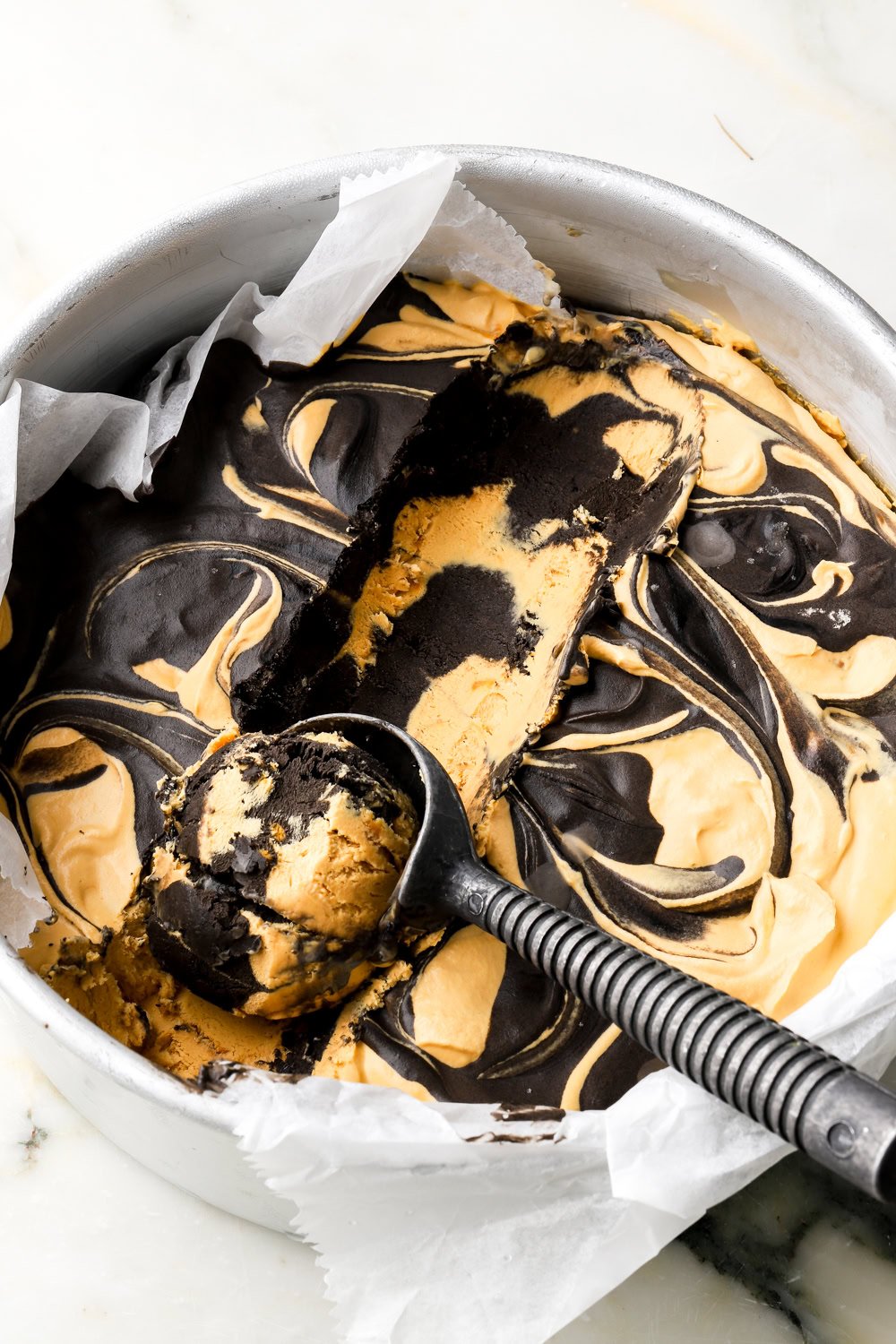 marbled dulce de leche ice cream in a pan with a scoop