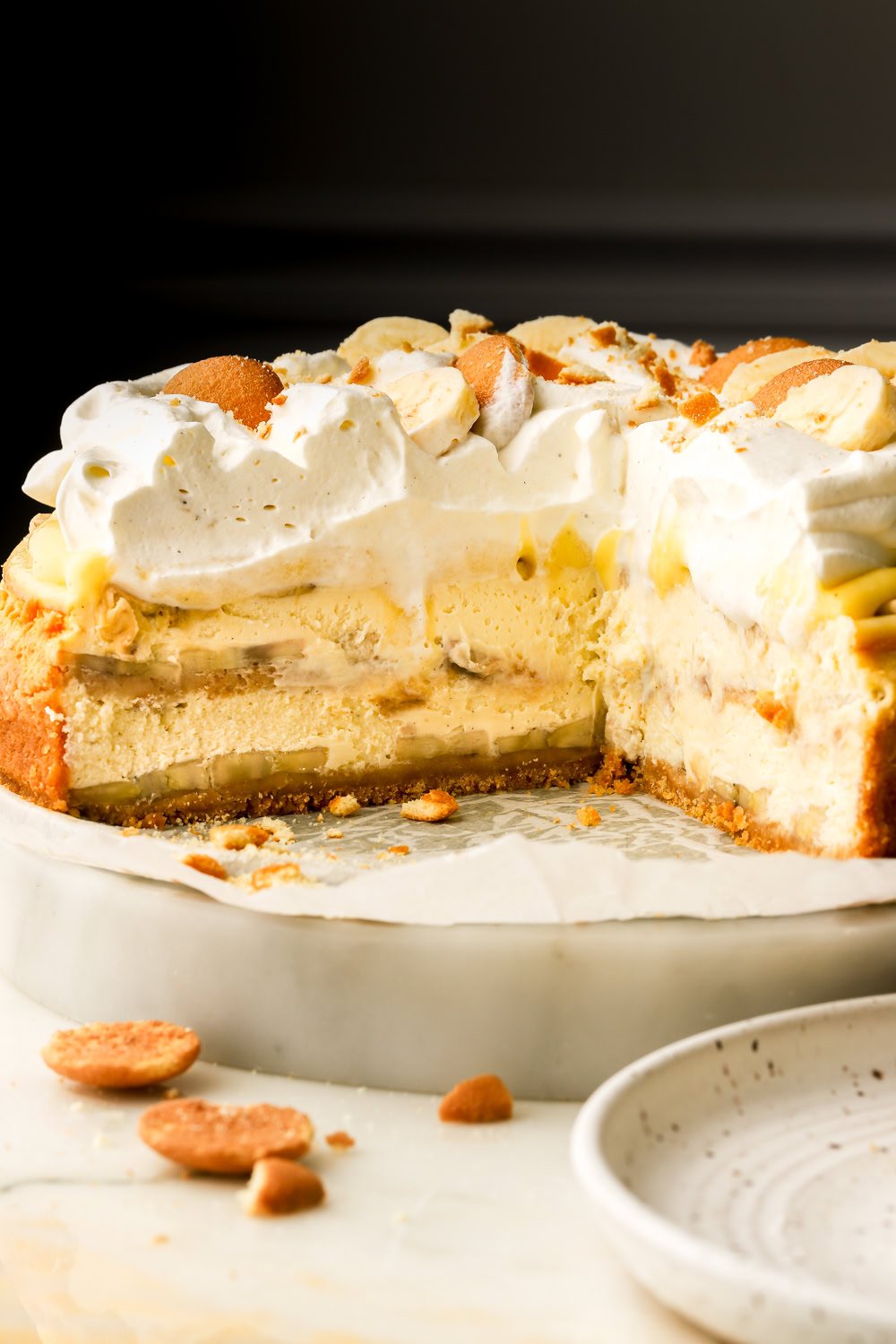 Banana pudding cheesecake sliced into revealing layers of cheesecake, banana slices, vanilla pudding and whipped cream